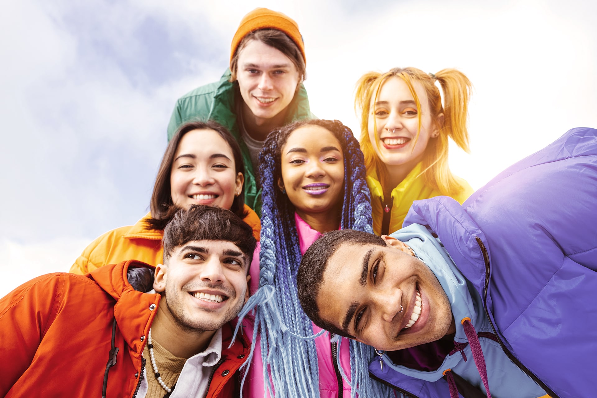 Sechs Jugendliche mit bunten Haaren und bunten Anziehsachen lächeln in die Kamera.