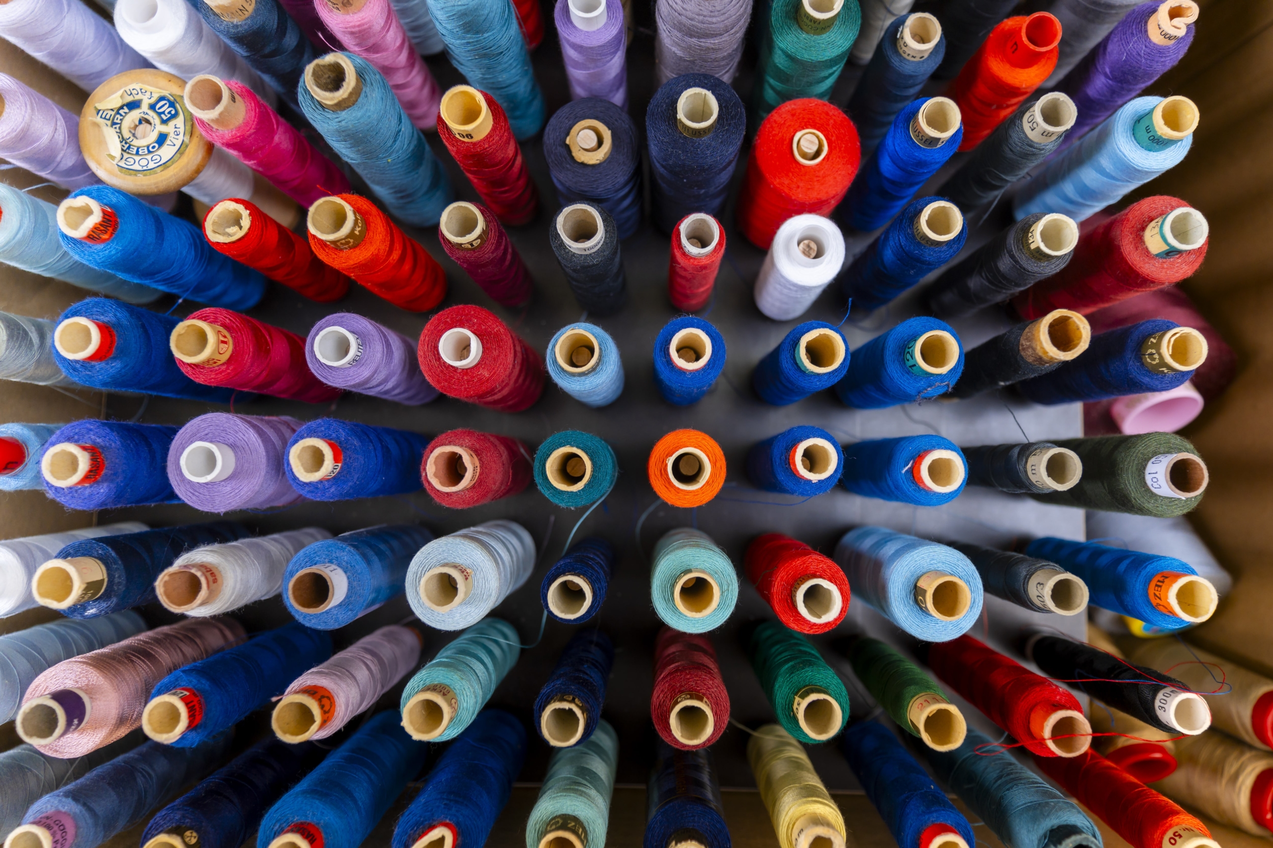 eine Kiste voll buntem Nähgarn von oben fotografiert