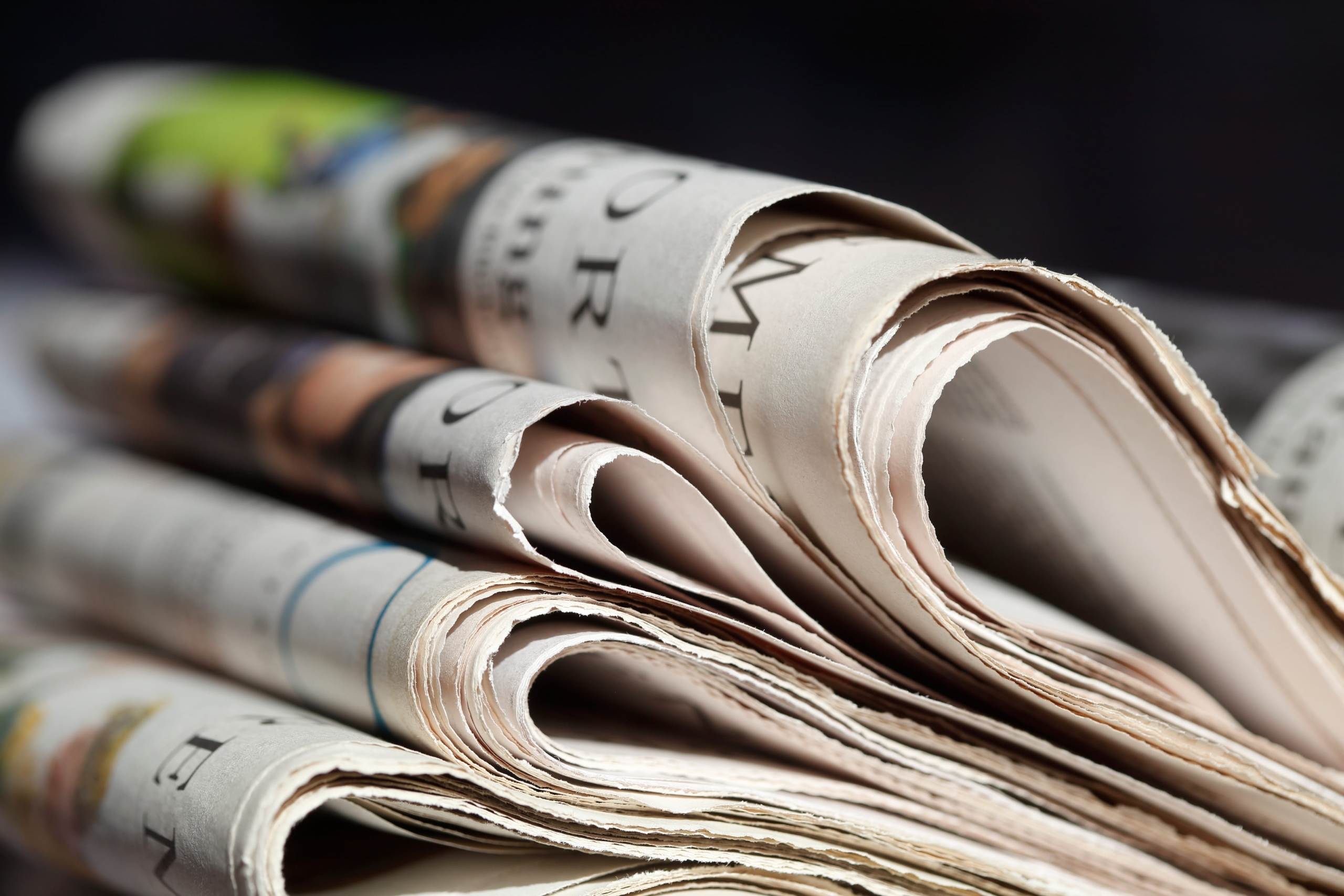 Ein Stapel Zeitungen liegt auf einem Tisch.